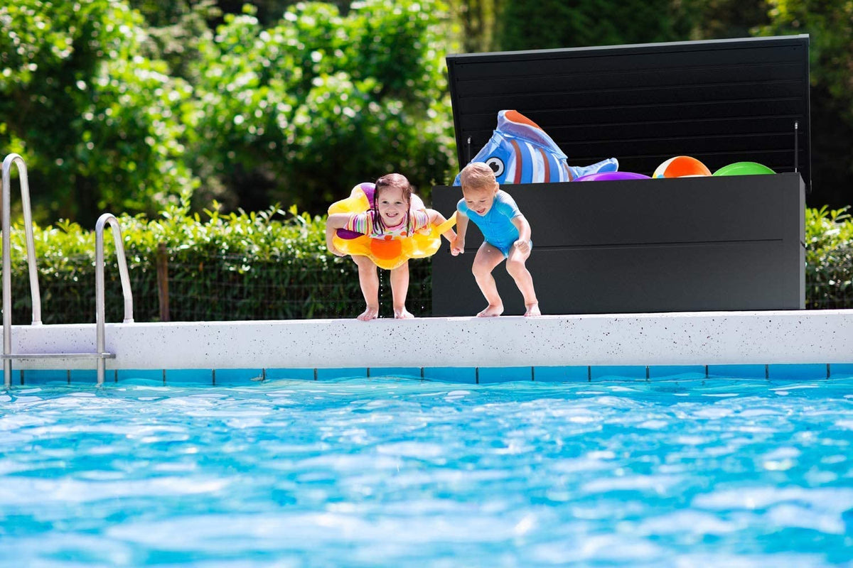Vista de ambiente en una piscina con la Caja de Almacenamiento para Exterior de acero Resistente con Tapa para exterior - Ahorra Espacio - 135x65x69 cm, Vista general con tapa abierta color gris antracita. Benni-Boy ILESTO