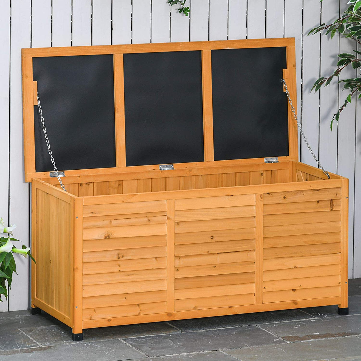 Patio exterior con el arcón de madera de interior y exterior con Tapa y Diseño tipo Persiana 127x56x60 cm color Natural. Outsunny