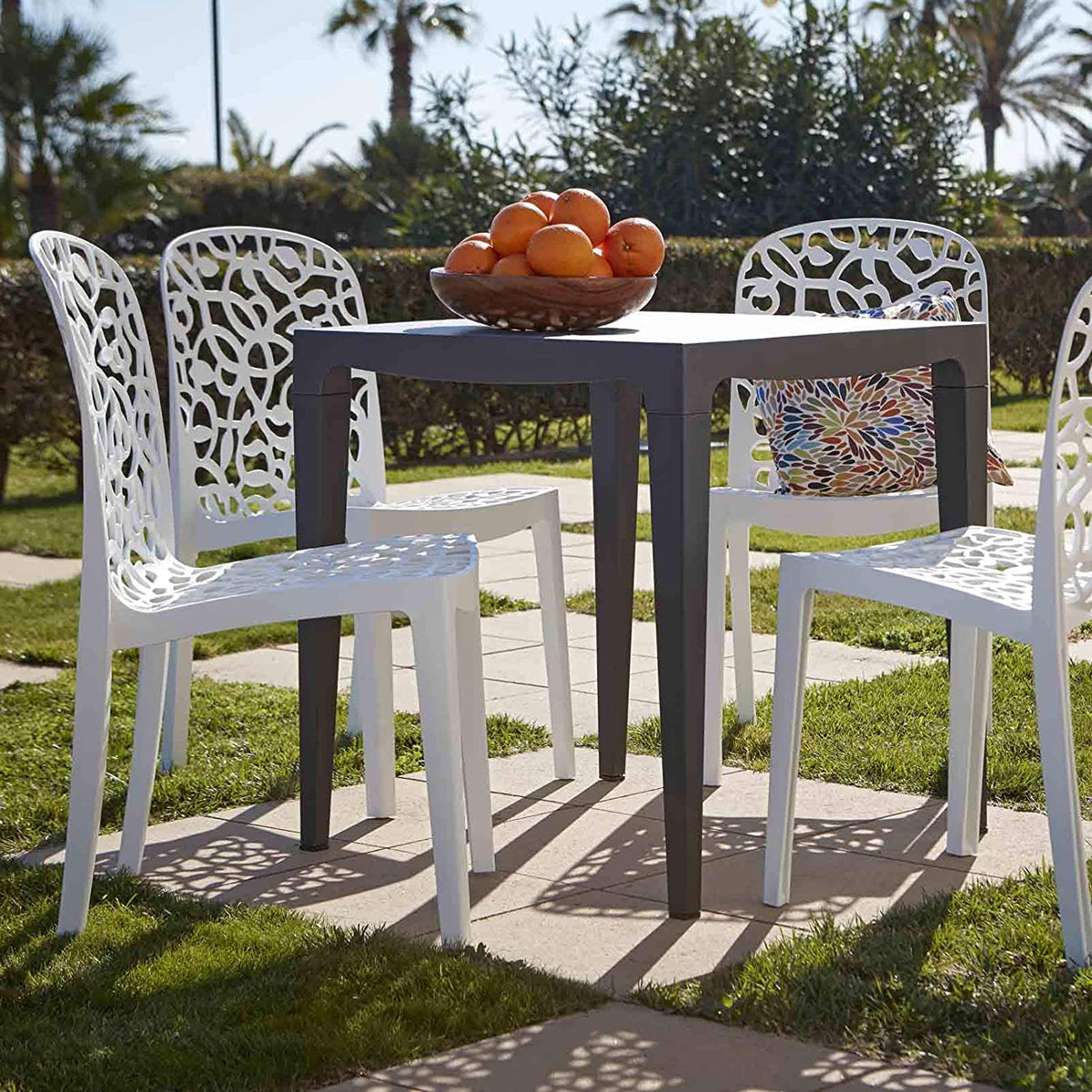 Set de sillas Shaf Flora y mesa en bonito jardín con una fuente de narenjas en un día soleado