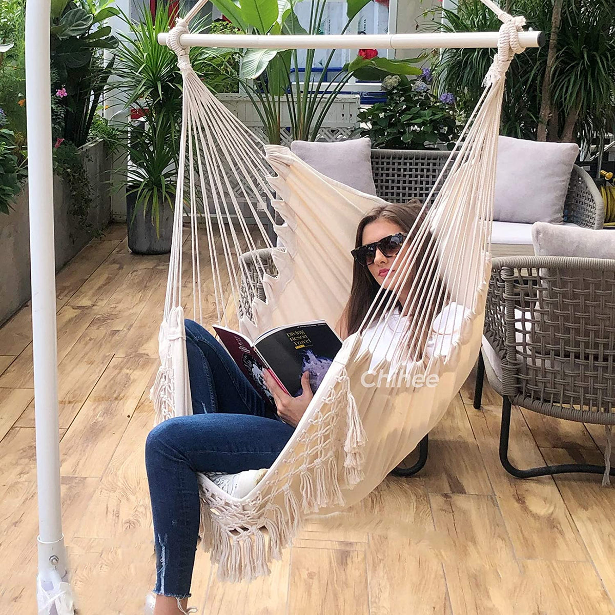 Ambiente de terraza con joven leyendo revista en la Silla colgante Grande para Relax hecha de algodón con Borlas Elegantes Metal Combinación de 3 Secciones Desmontable. Silla colgante Chihee