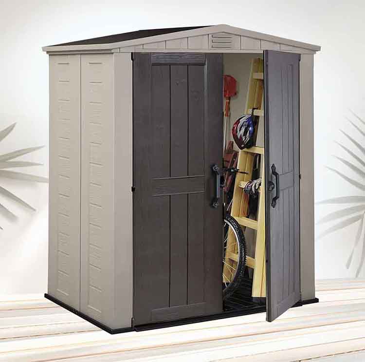 Caseta Keter Factor 3x6 con puerta entreabierta en fondo de terraza con logos de Maxjardín y Keter